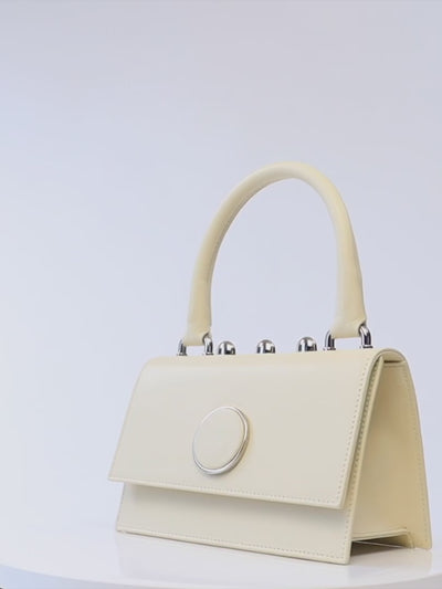 Ambra Bag – Italian crafted handbag with detachable shoulder strap, flap closure, silver-toned accessories, and three rounded studs.